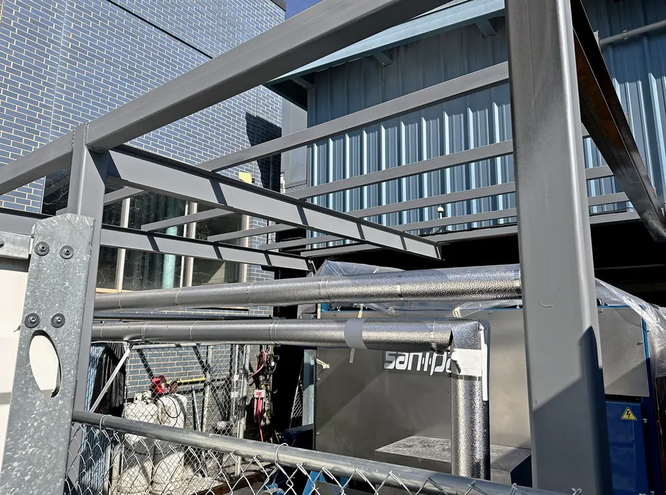 Steel canopy frame in gray primer over the San-I-Pak unit